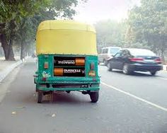 a green and yellow truck driving down a street next to a tree filled road with cars