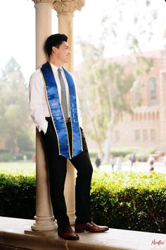 a man wearing a blue sash standing next to a pillar