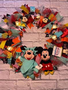 a mickey mouse and minnie mouse wreath on a brick wall with lights in the background