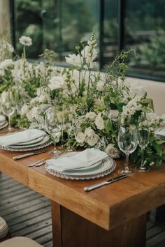 the table is set with white flowers and place settings