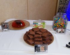 a table topped with cake and candies on top of a white tablecloth covered table