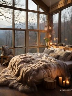 a large bed sitting next to a window covered in blankets and pillows on top of a wooden floor