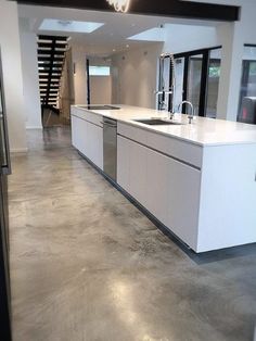 an empty kitchen with white cabinets and stainless steel appliances in the center, is seen through a glass door