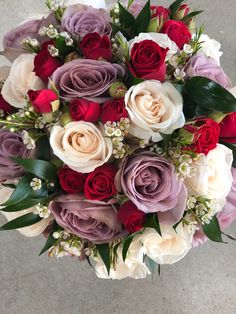 a bouquet of flowers with red, white and purple roses in the center is shown