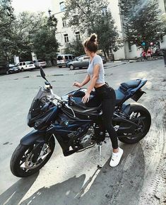 a woman sitting on top of a black motorcycle