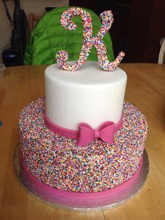 a white cake with sprinkles and a pink bow on top that says 25