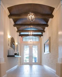 an entry way with tile floors and wooden beams on the ceiling is flanked by two framed pictures