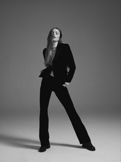 a woman is posing in a black suit