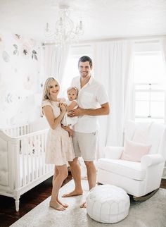 a man and woman standing in front of a white crib with a baby girl