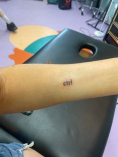 a person's arm with the word ctl tattooed on it, in front of a table