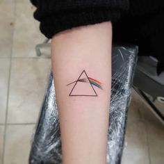 a small triangle tattoo with a rainbow on the inside of it's left arm