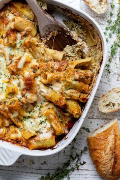 a casserole dish filled with pasta, cheese and bread on a white table