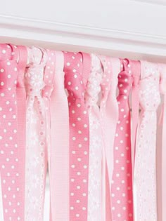 pink and white polka dot ribbon hanging from the side of a window curtain with lace trim