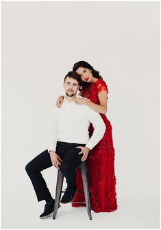 a man and woman pose for a photo in front of a white background, wearing red