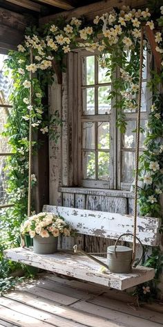 an old wooden porch swing with flowers on it and potted plants hanging from the side