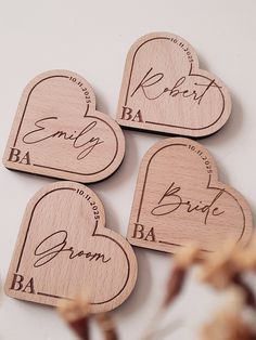 four wooden heart shaped magnets with names and hearts engraved on the front, two are shown