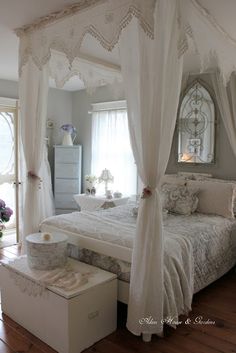 a white bed sitting inside of a bedroom next to a dresser and window covered in curtains