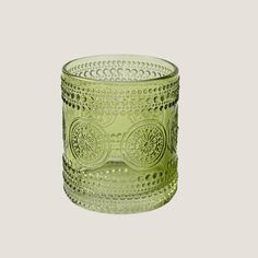 a green glass candle holder sitting on top of a table