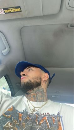 a man sitting in the back seat of a car wearing a baseball cap and looking up