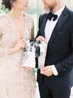 a man and woman standing next to each other in formal wear looking at each other