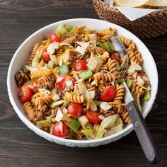 a white bowl filled with pasta salad next to a basket of tortilla chips