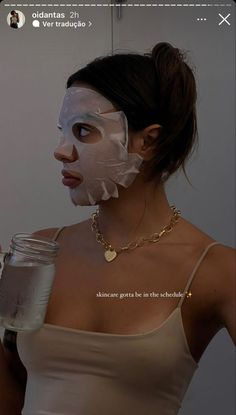 a woman holding a glass with a face mask on her head and looking at the camera