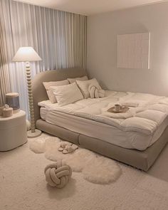 a white bed sitting on top of a floor next to a lamp