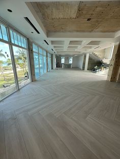 an empty room with wooden floors and large windows overlooking the ocean in front of it