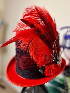 Colorful red top hat trimmed with black and red accessories and feathers