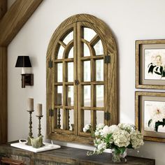 an old dresser with flowers and candles on it in front of a wall mounted window