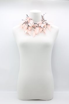 a white mannequin with a pink flowered necklace on it's neck