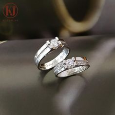 two wedding bands with diamonds on them sitting on a black surface next to each other