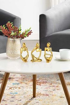 three gold figurines sitting on top of a white coffee table