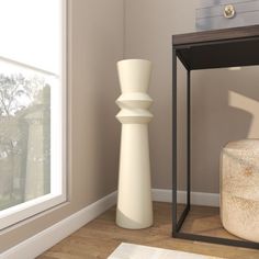 a white vase sitting on top of a hard wood floor next to a tall white sculpture