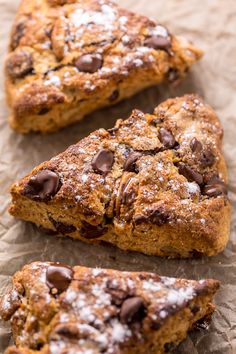 three pieces of chocolate chip scones sitting on top of a piece of parchment paper