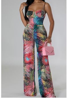 A woman wearing a vibrant Fitted Summer Jumpsuits And Rompers With Tropical Print, Fitted Tropical Print Jumpsuits And Rompers For Summer, Chic Multicolor Strapless Jumpsuit For Summer, Sleeveless Multicolor Tropical Jumpsuits And Rompers, Multicolor Tropical Print Jumpsuits And Rompers For Beach Season, Multicolor Tropical Print Jumpsuits For Beach Season, Summer Multicolor Tropical Print Jumpsuits And Rompers, Multicolor Strapless Jumpsuit For Vacation, Sleeveless Tropical Print Jumpsuits And Rompers