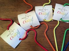 four different colored paper clips sitting on top of a wooden table next to each other