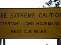 there is a yellow sign that says, please extreme caution constant land movement next to 8 miles