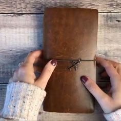 a woman is holding a brown leather journal