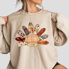 a woman wearing a sweatshirt with a turkey graphic on the front and side, while holding her hands behind her back