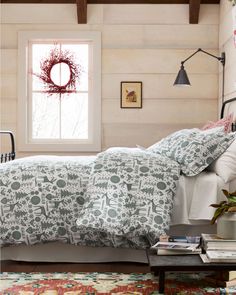 a bed room with a neatly made bed and a wreath on the window sill