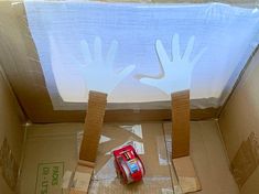 a cardboard box with some handprints on it and a red car in the middle