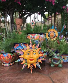 many colorful pots with plants in them on the ground and one has a sun face painted on it