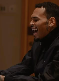 a man laughing while sitting in front of a laptop computer