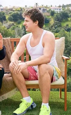 a man sitting on top of a chair next to a woman in a white tank top