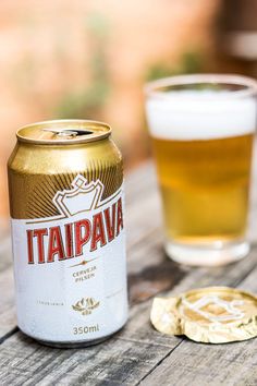 a close up of a can of beer next to a glass on a wooden table