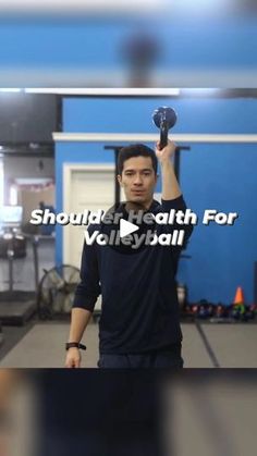 a man holding up a ball in a gym