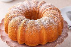 a bundt cake with powdered sugar on top sits on a pink platter