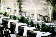 a long table set with place settings and greenery