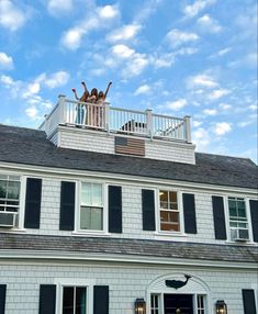 two people standing on top of a white house